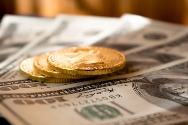 gold colored coins on usd bills laid out